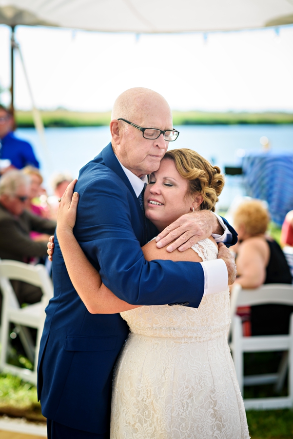 A father of the bride holds his daughter while they dance at her wedding.